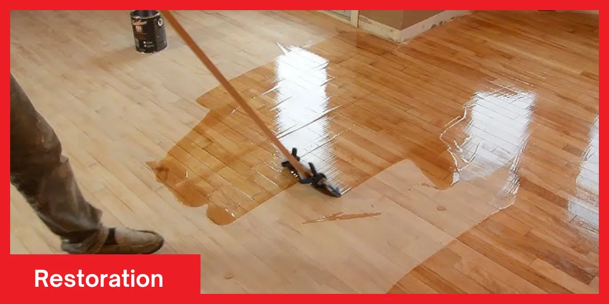 Person applying a glossy wood finish during a floor restoration process