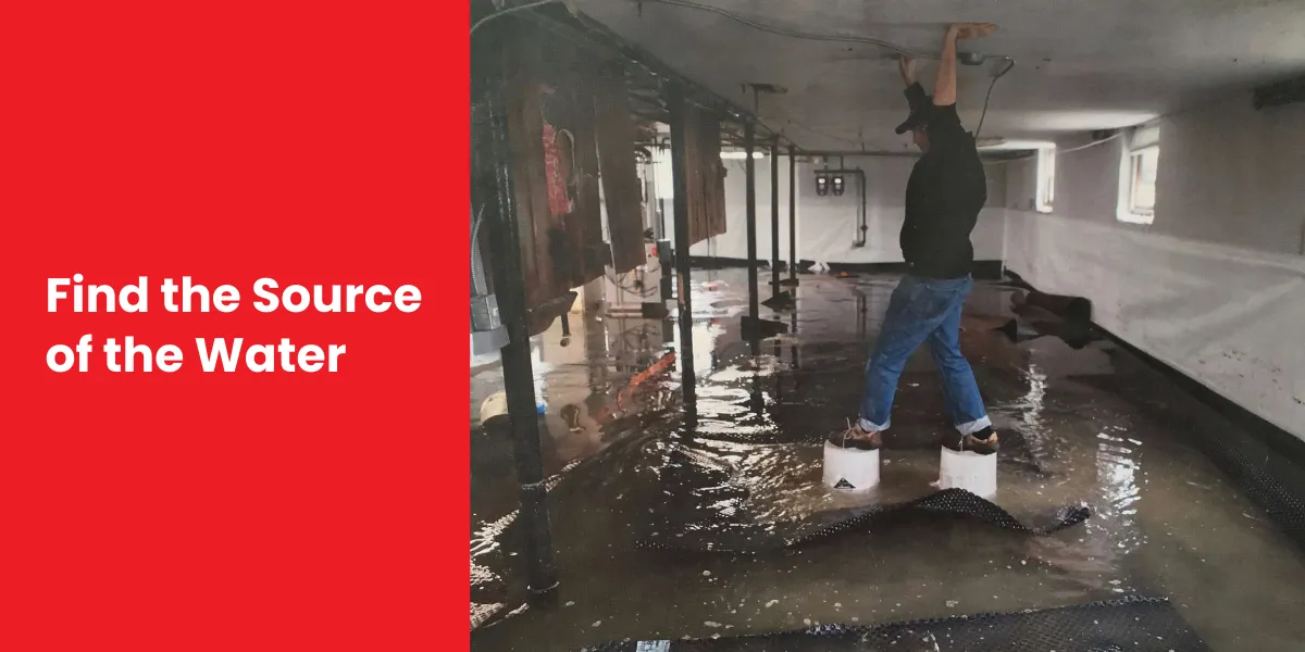 A person standing on blocks in a waterlogged crawl space, inspecting the source of water damage.