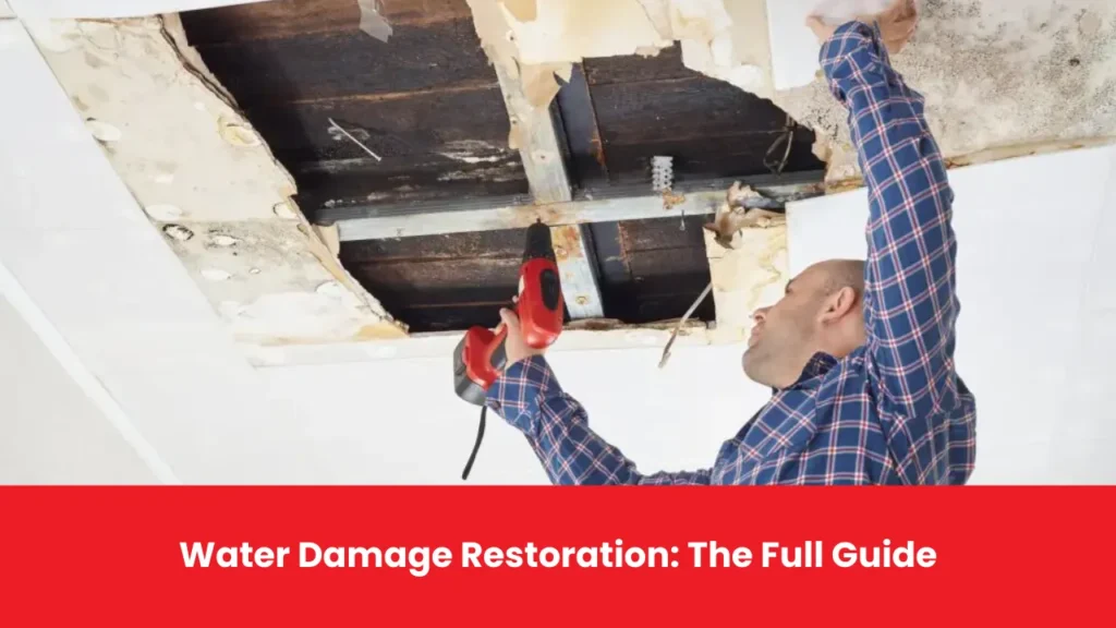 A professional using a drill to repair water-damaged ceiling drywall during the restoration process.