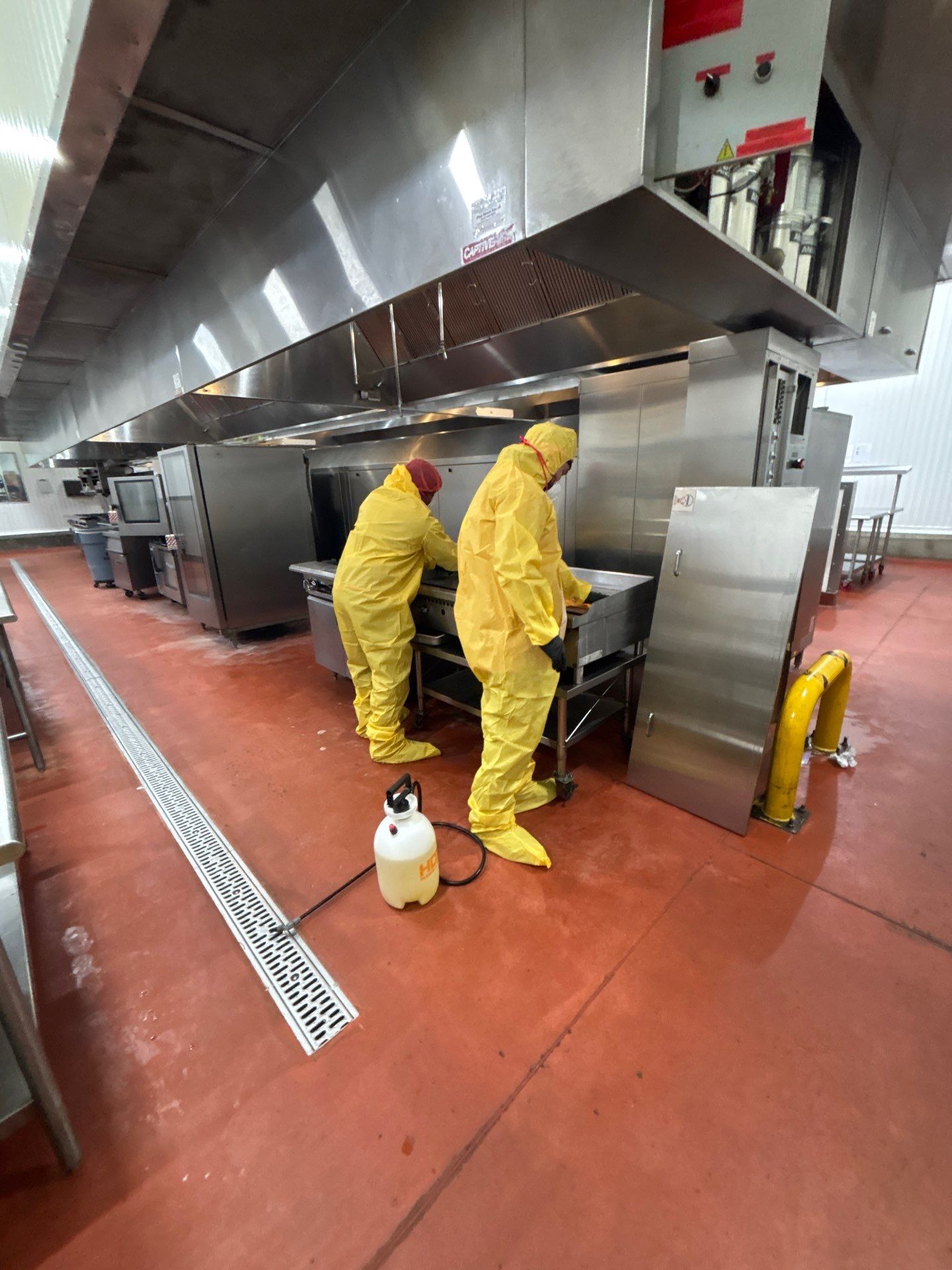 SOS Restoration crew in protective suits cleaning a commercial kitchen floor in Inglewood, CA