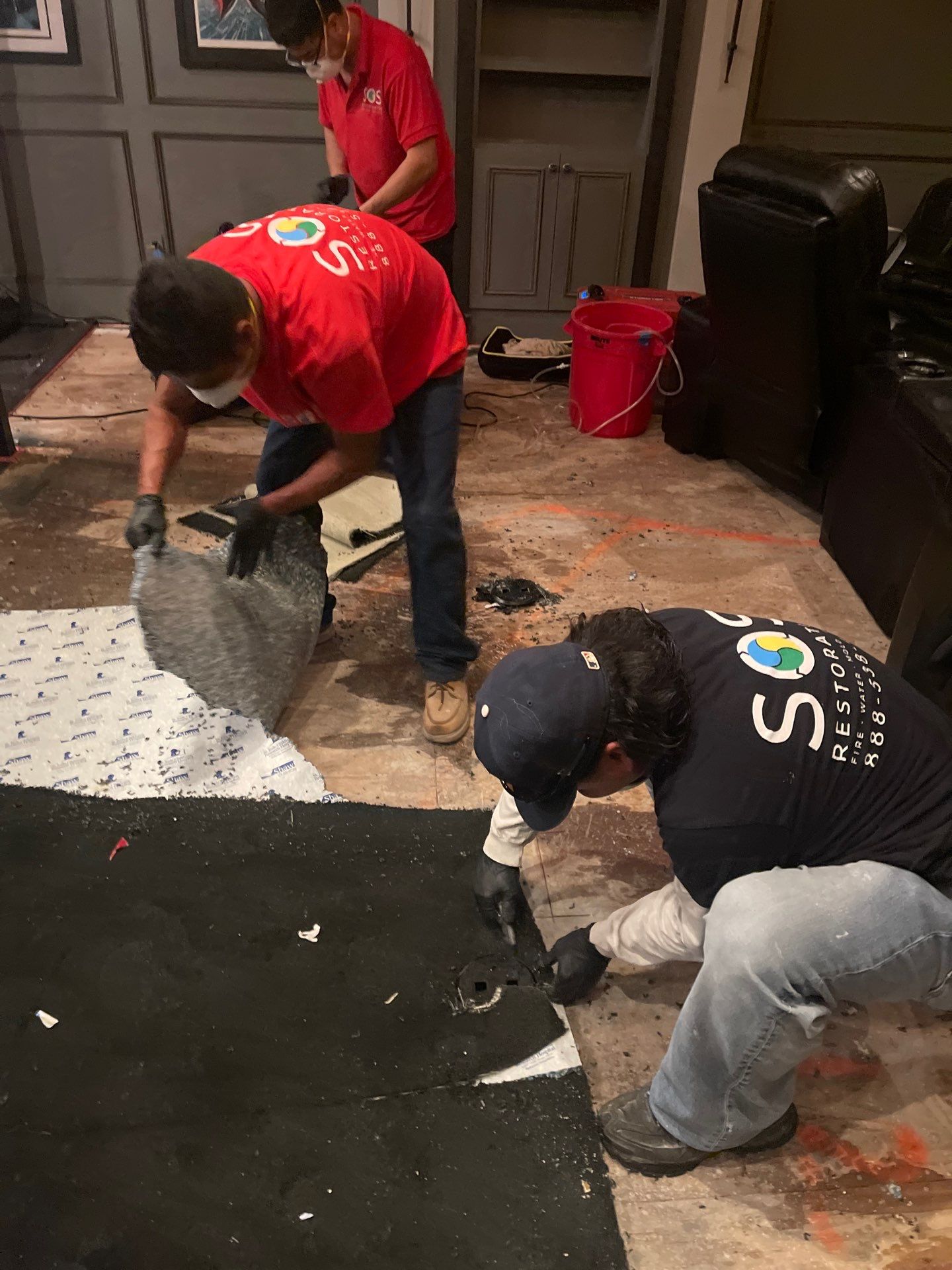 SOS Restoration technicians removing water-damaged carpet and padding in Orange, CA