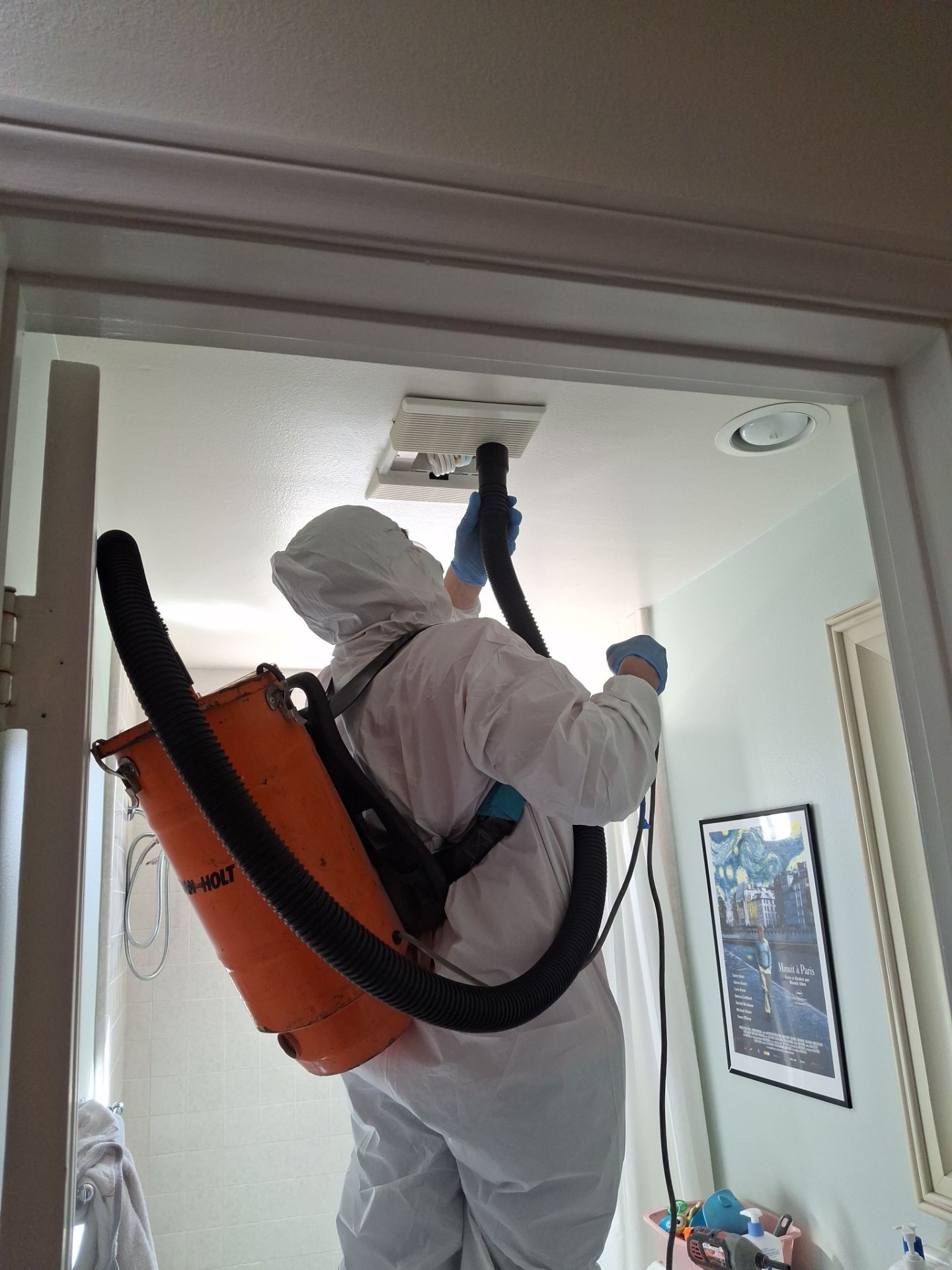 SOS Restoration technician HEPA vacuuming a bathroom exhaust vent during mold remediation in Santa Monica, CA